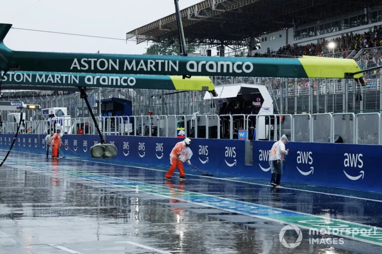 Flooded race track with marshals sweeping away standing water after torrential rain at the São Paulo Grand Prix